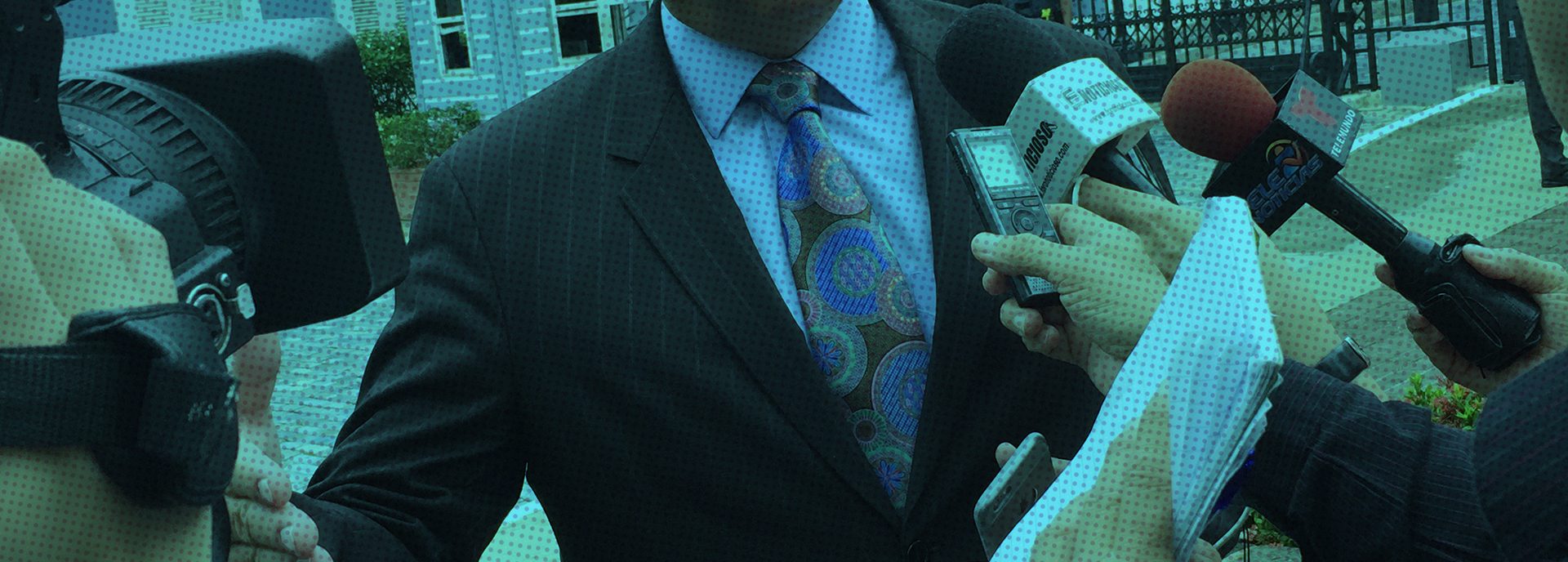Reporters holding a camera, microphones, and a notebook surround an interviewee.